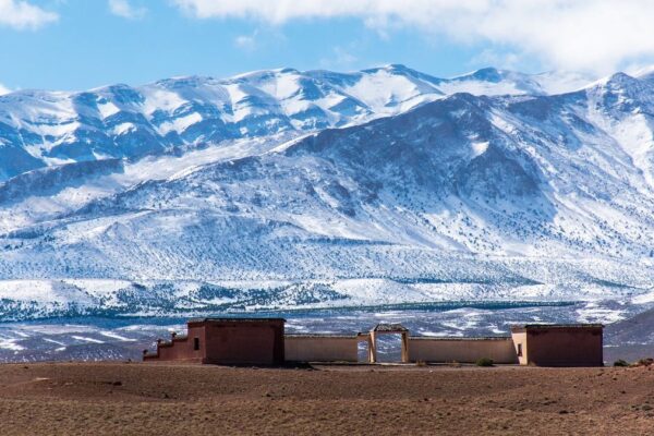 A photo of a snowy mountain range with a Moroccan building in the foreground