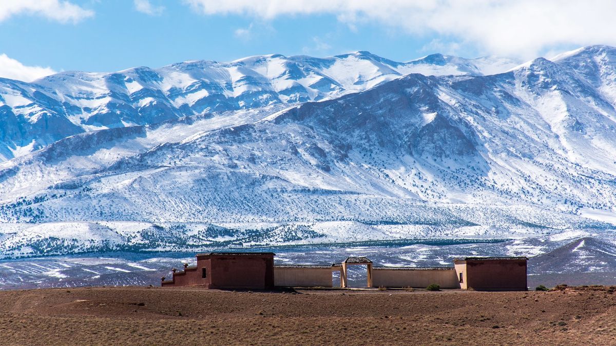 A photo of a snowy mountain range with a Moroccan building in the foreground