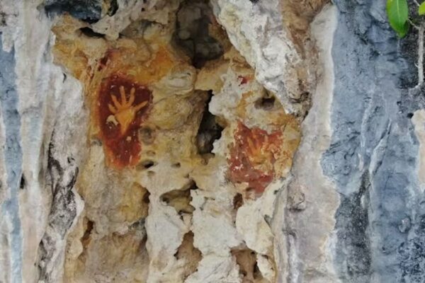 Handprints in orange pigment on a rocky wall