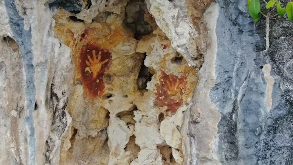 Handprints in orange pigment on a rocky wall