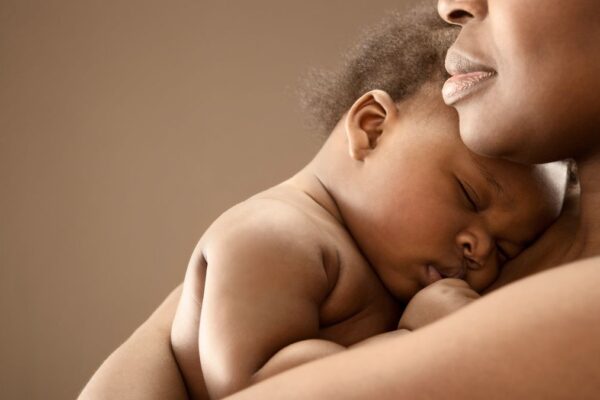 A Black woman holds a baby close to her chest