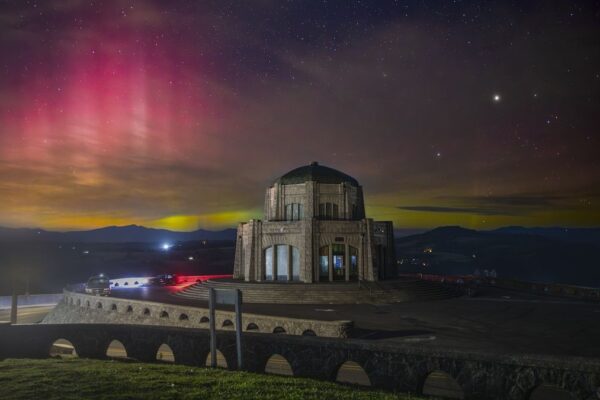 Auroras behind a domed building on a hill