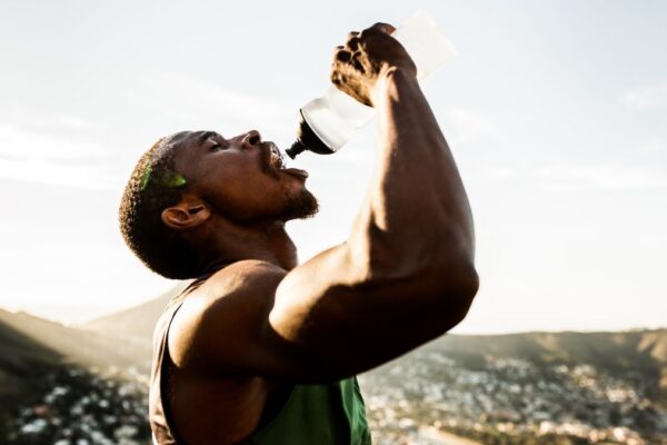 A man in athletic apparel squeezes water into his mouth from a water bottle