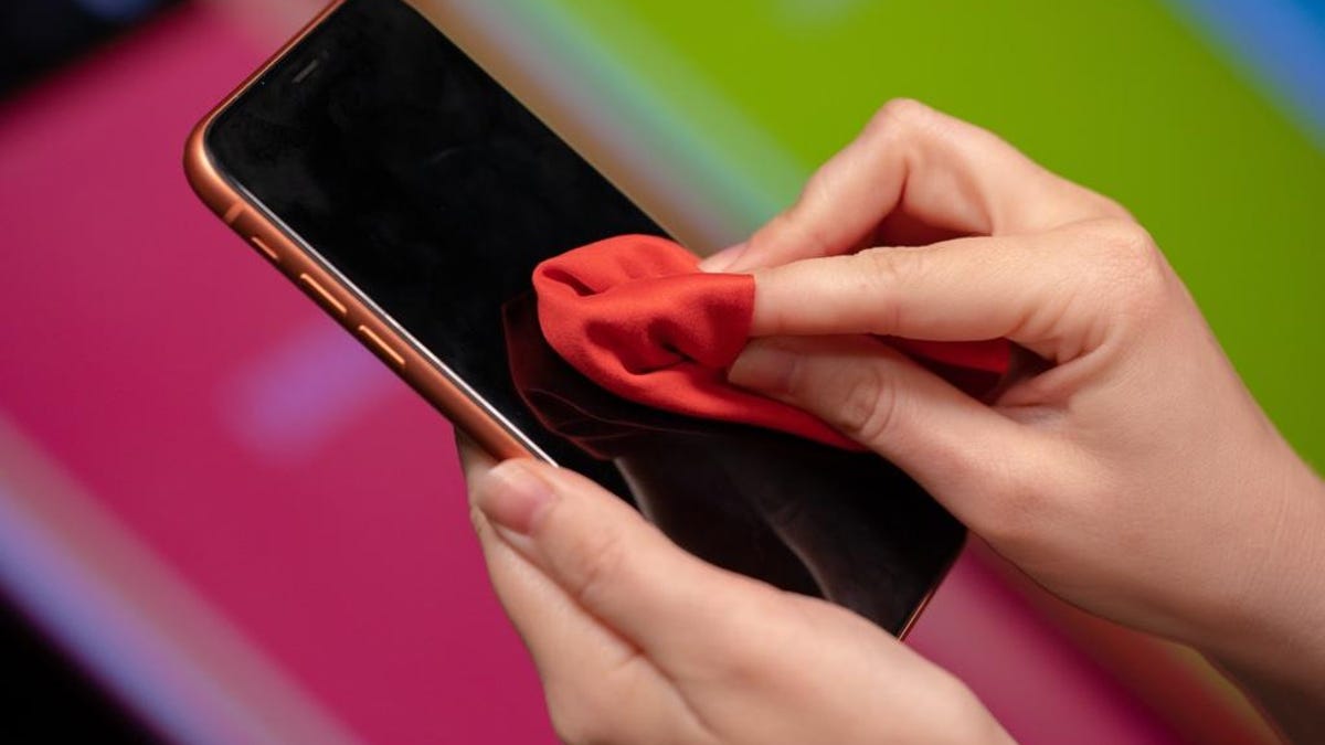 person cleaning a phone screen with a cloth