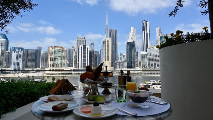 Breakfast is laid on a round table on a terrace with views of skyscrapers